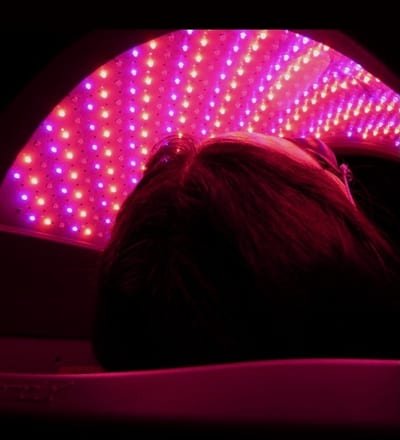 Client lying under the LED light therapy canopy during a session